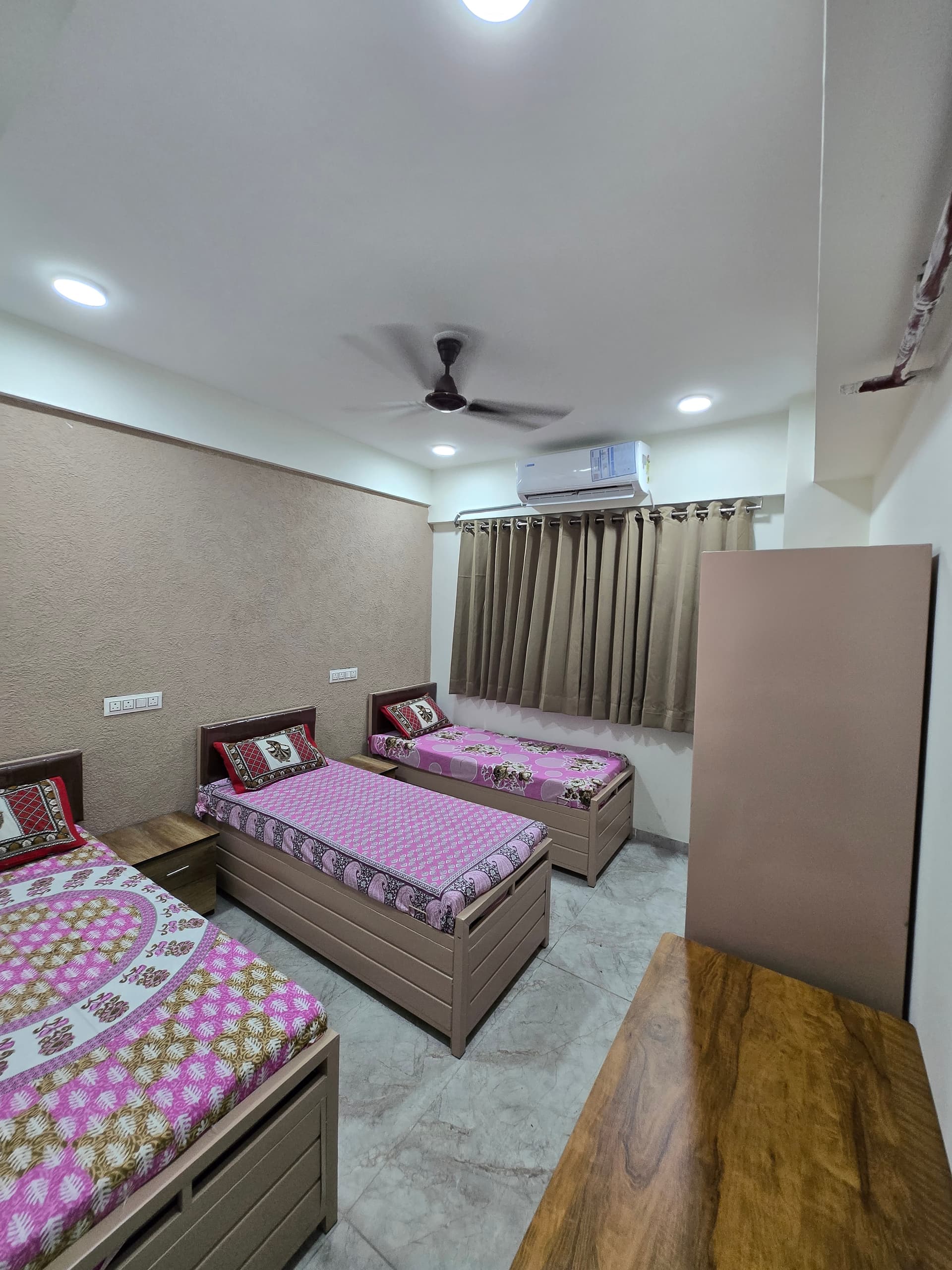 Triple sharing room with individual beds and desks at Mansarovar Girls PG, Ahmedabad